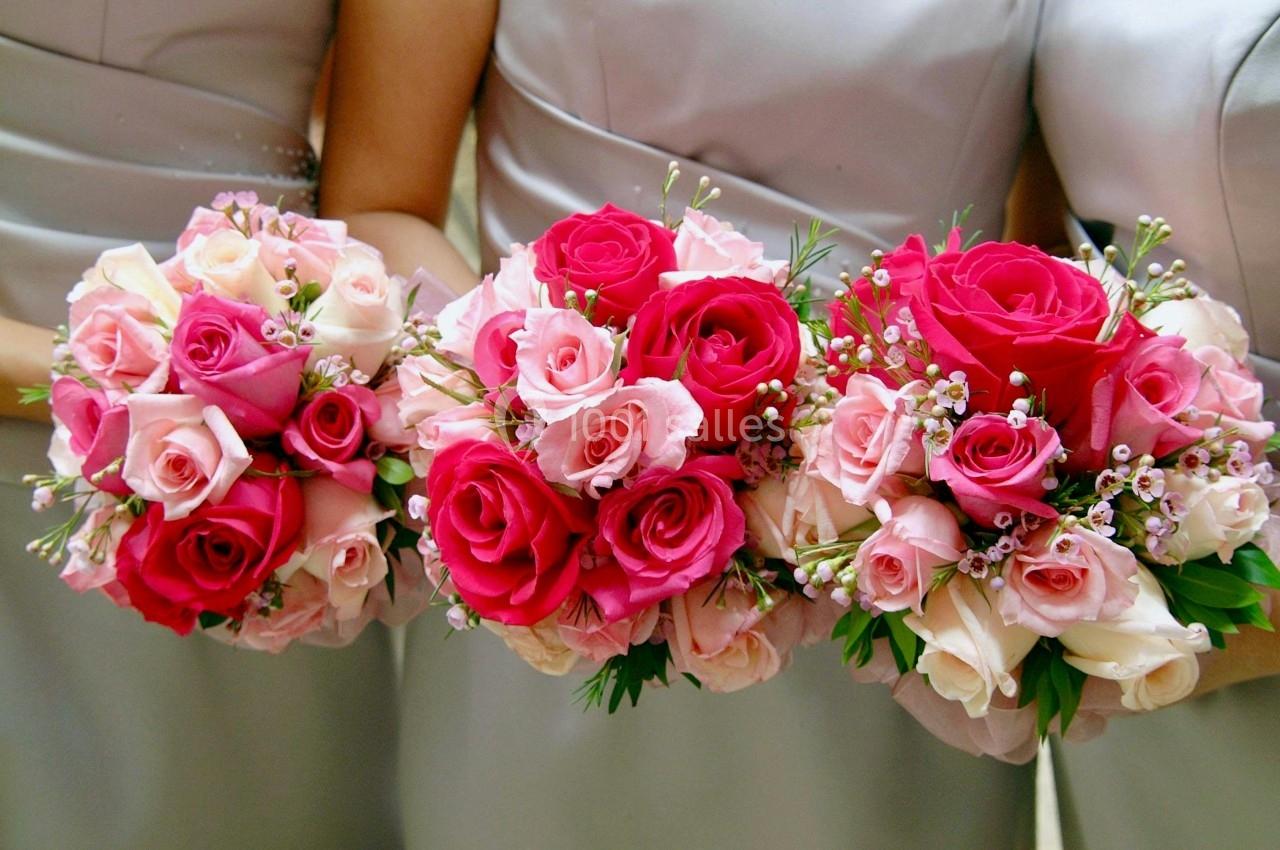 Trois bouquets de roses roses et blanches tenus par des personnes en robes grises.