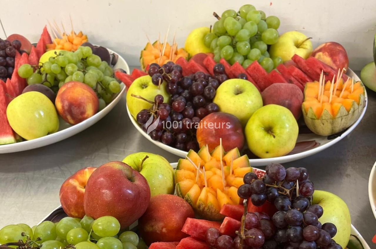 Assortiment de fruits frais comprenant pommes, raisins, pastèques, melons et nectarines disposés sur des plateaux.