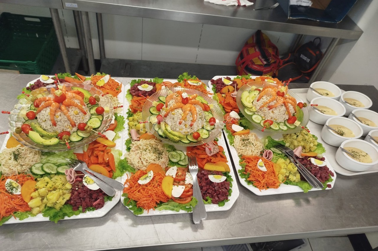 Plateaux de crudités variées avec légumes frais, œufs durs et riz, accompagnés de bols de soupe sur un plan de travail.