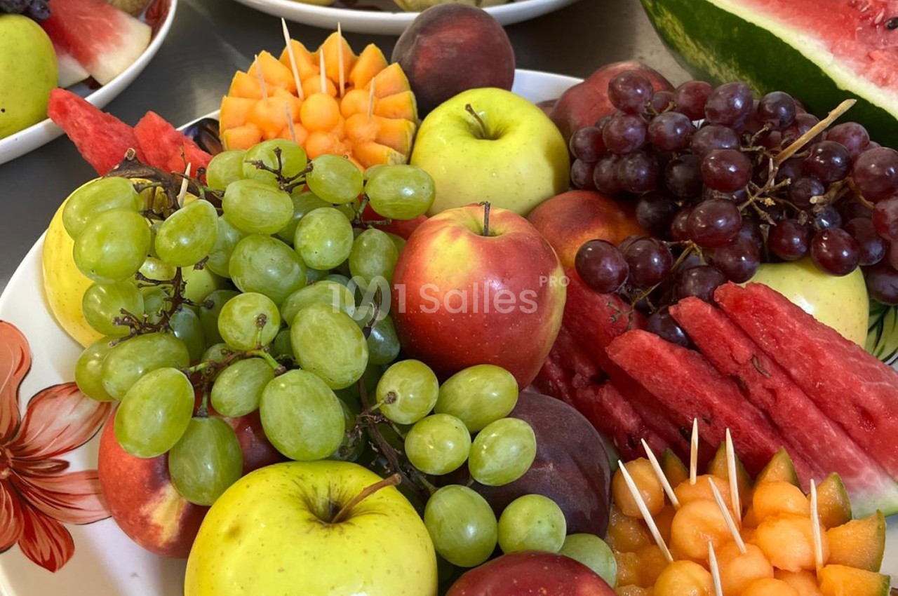 Assortiment de fruits frais comprenant pommes, raisins, pastèque et melon, joliment disposés sur une assiette.
