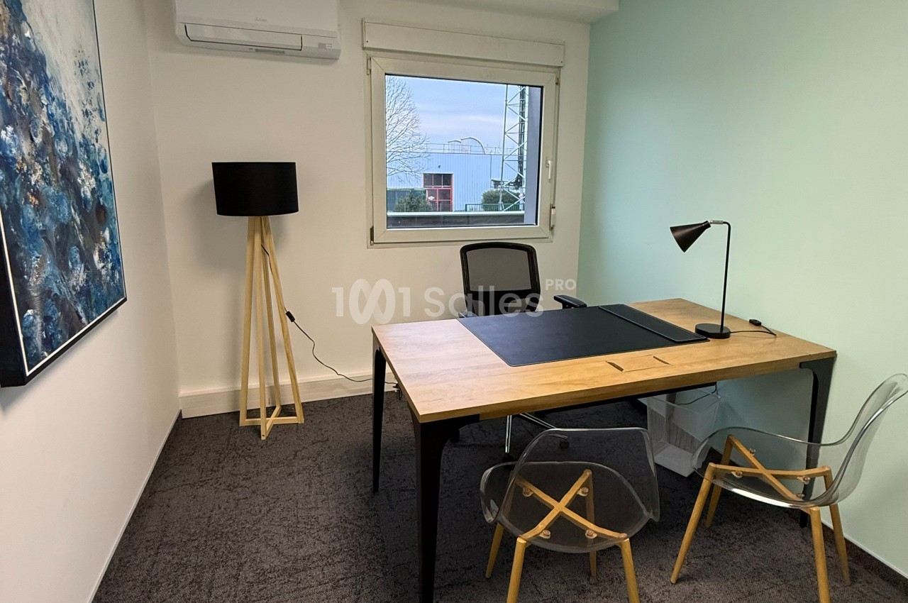 Bureau lumineux avec un grand bureau en bois, deux chaises transparentes, une lampe noire et une fenêtre donnant sur l…