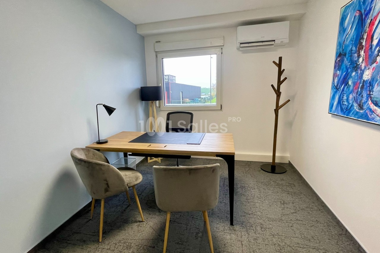 Bureau lumineux avec un bureau en bois, deux chaises, une lampe, un porte-manteau et une fenêtre donnant sur l'extérieur.