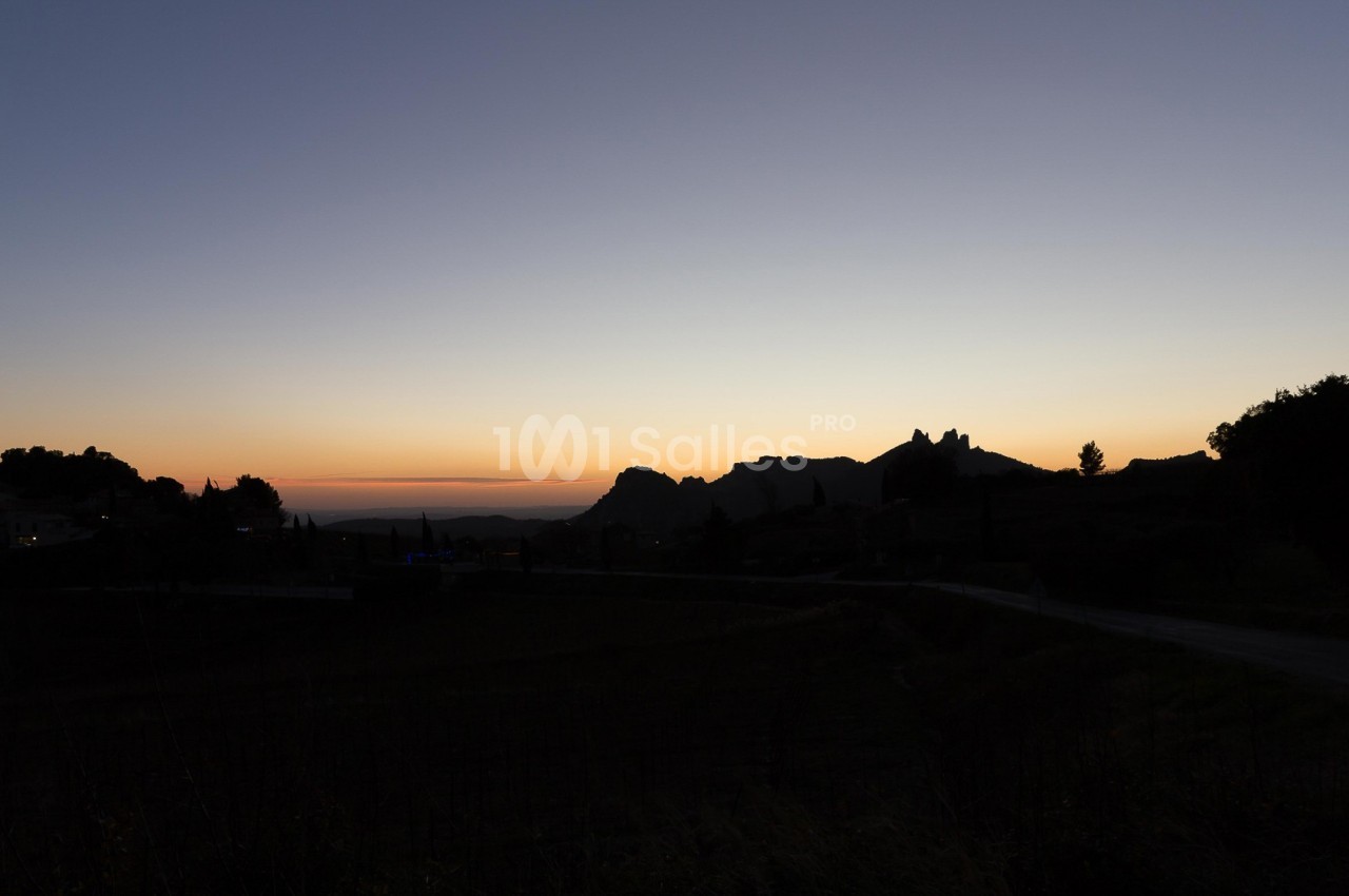 Paysage au crépuscule avec des silhouettes de collines, d'arbres et d'une route sous un ciel dégradé.