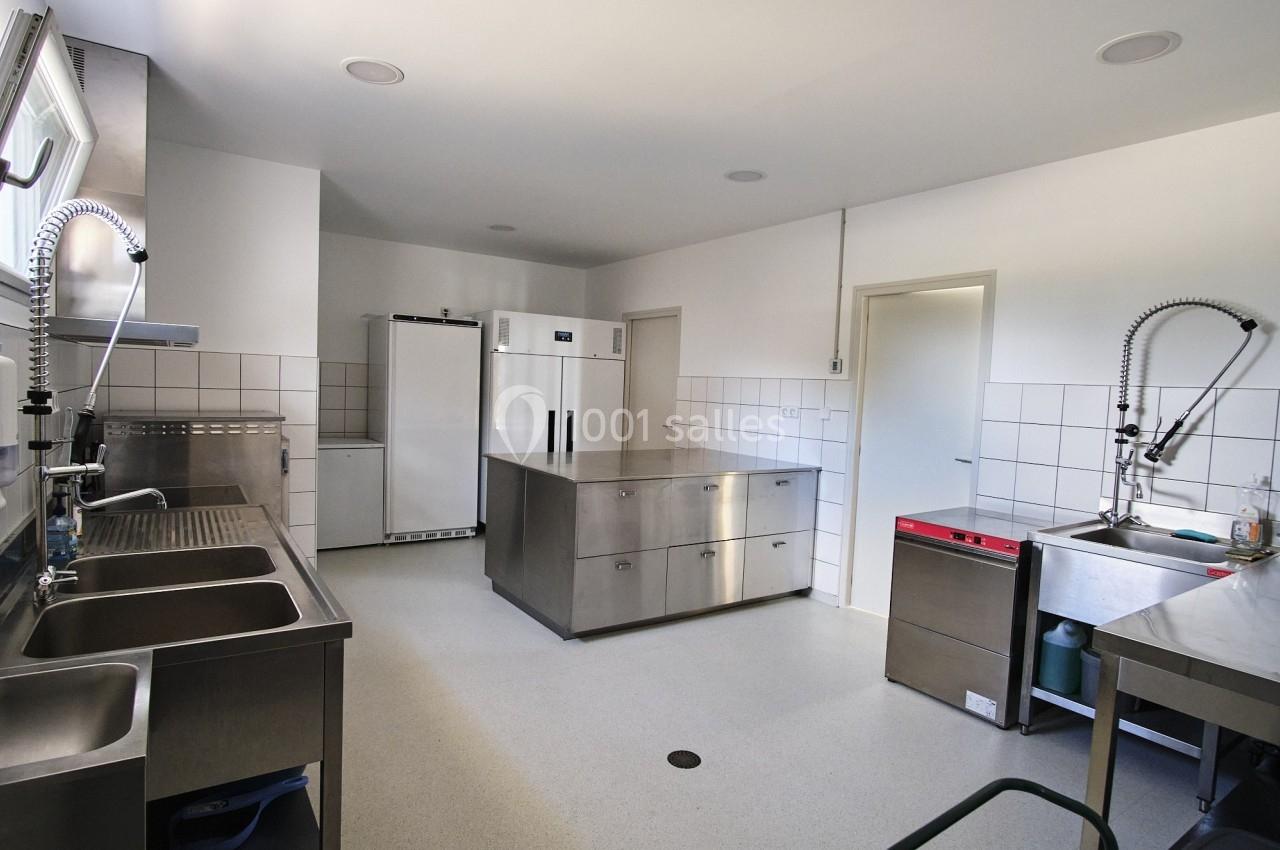 Cuisine professionnelle équipée avec plans de travail en inox, éviers, lave-vaisselle et réfrigérateurs.