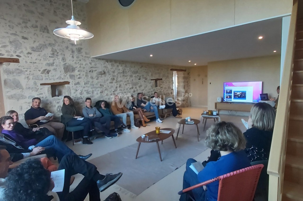 Un groupe de personnes assises dans une salle en pierre, regardant une présentation sur un écran.
