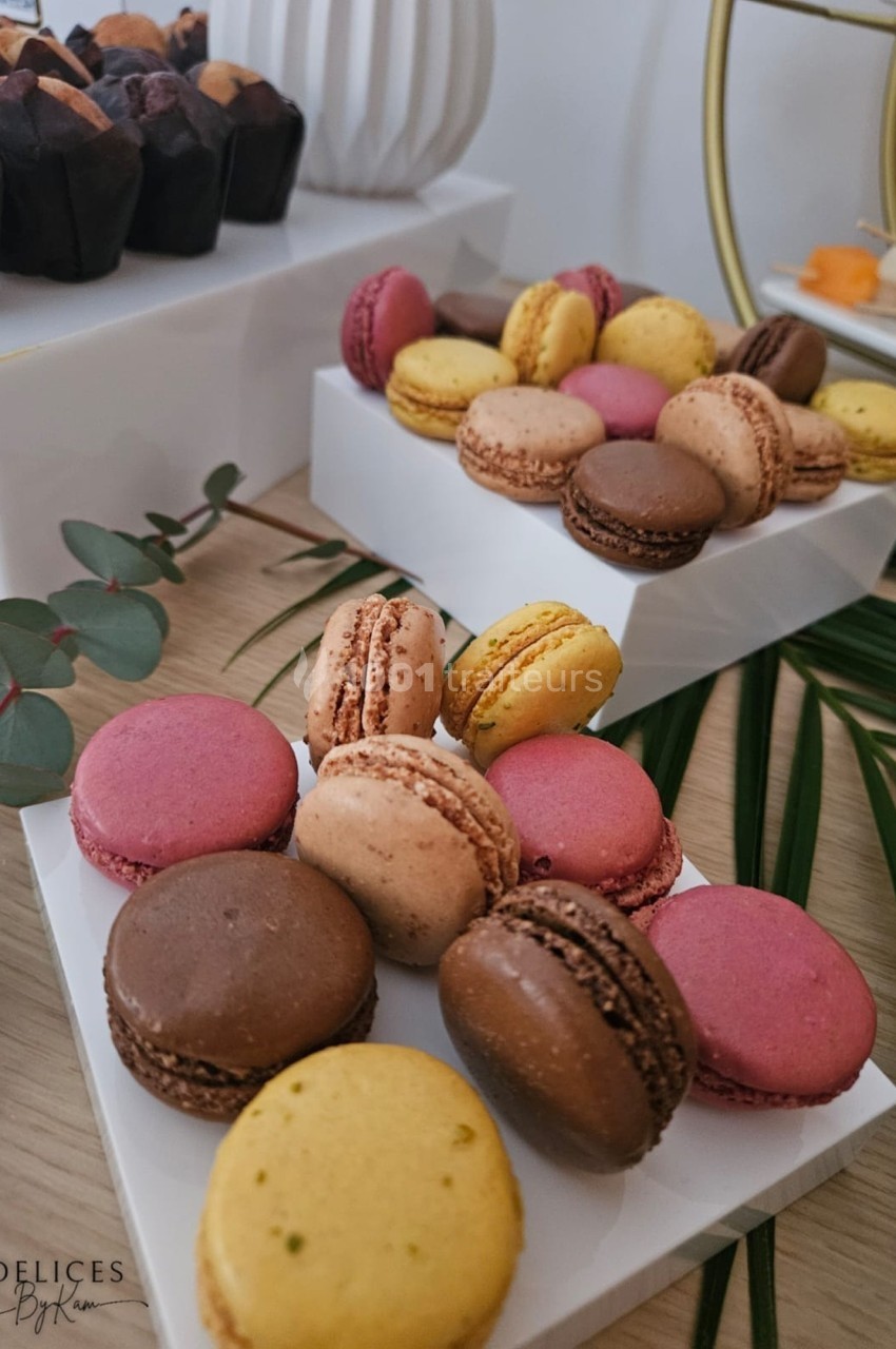 Plateaux de macarons colorés disposés sur une table en bois, décorée de feuilles et d'éléments naturels.