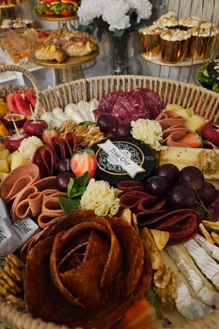 Plateau de charcuterie et fromages variés avec fruits, noix et crackers, présenté dans un panier en osier.