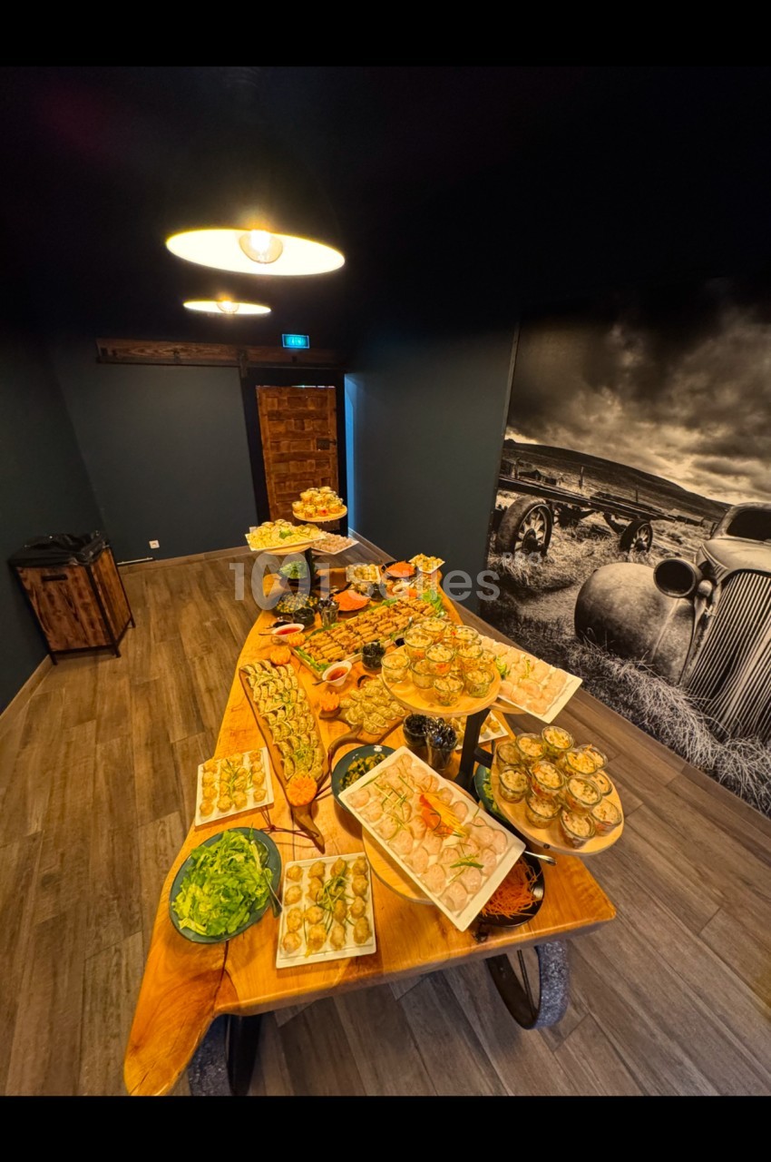 Table en bois garnie de divers plats et amuse-bouches dans une pièce sombre avec une décoration murale rétro.
