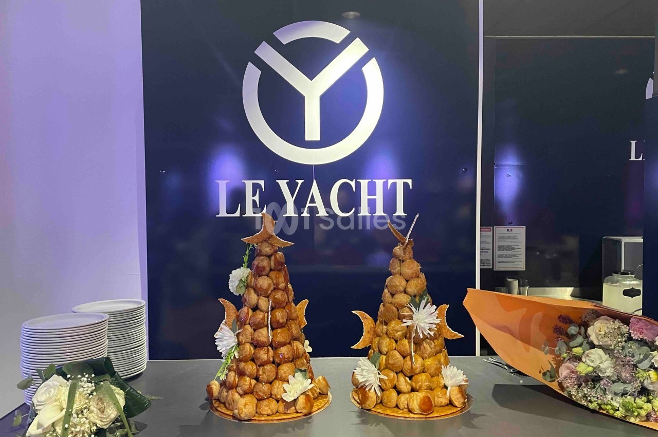 Deux pièces montées en choux décorées de fleurs et étoiles, posées sur un comptoir devant un logo ’Le Yacht’.