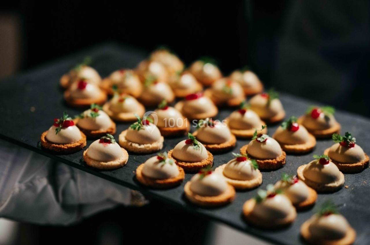 Plateau de bouchées apéritives garnies de mousse blanche, herbes fraîches et baies rouges.