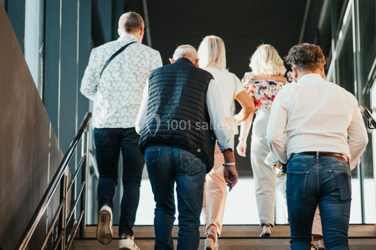 Un groupe de personnes monte un escalier dans un bâtiment lumineux.