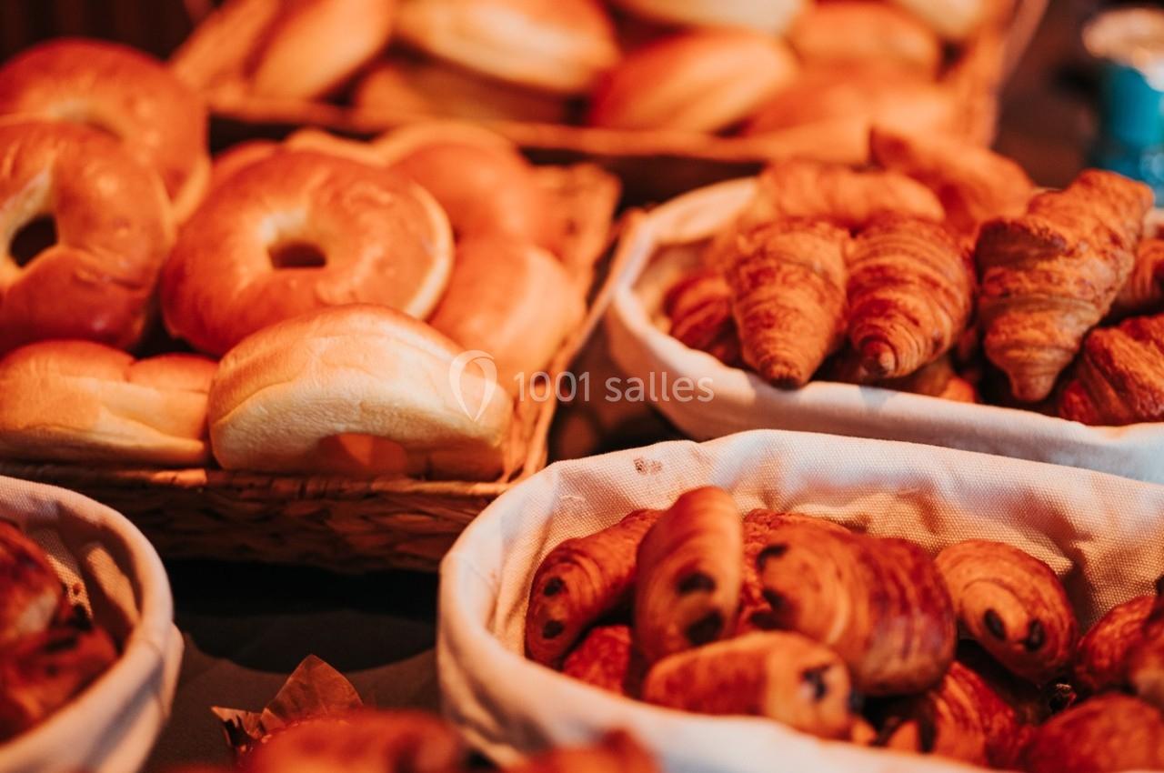Paniers contenant des croissants, pains au chocolat et bagels disposés sur une table.
