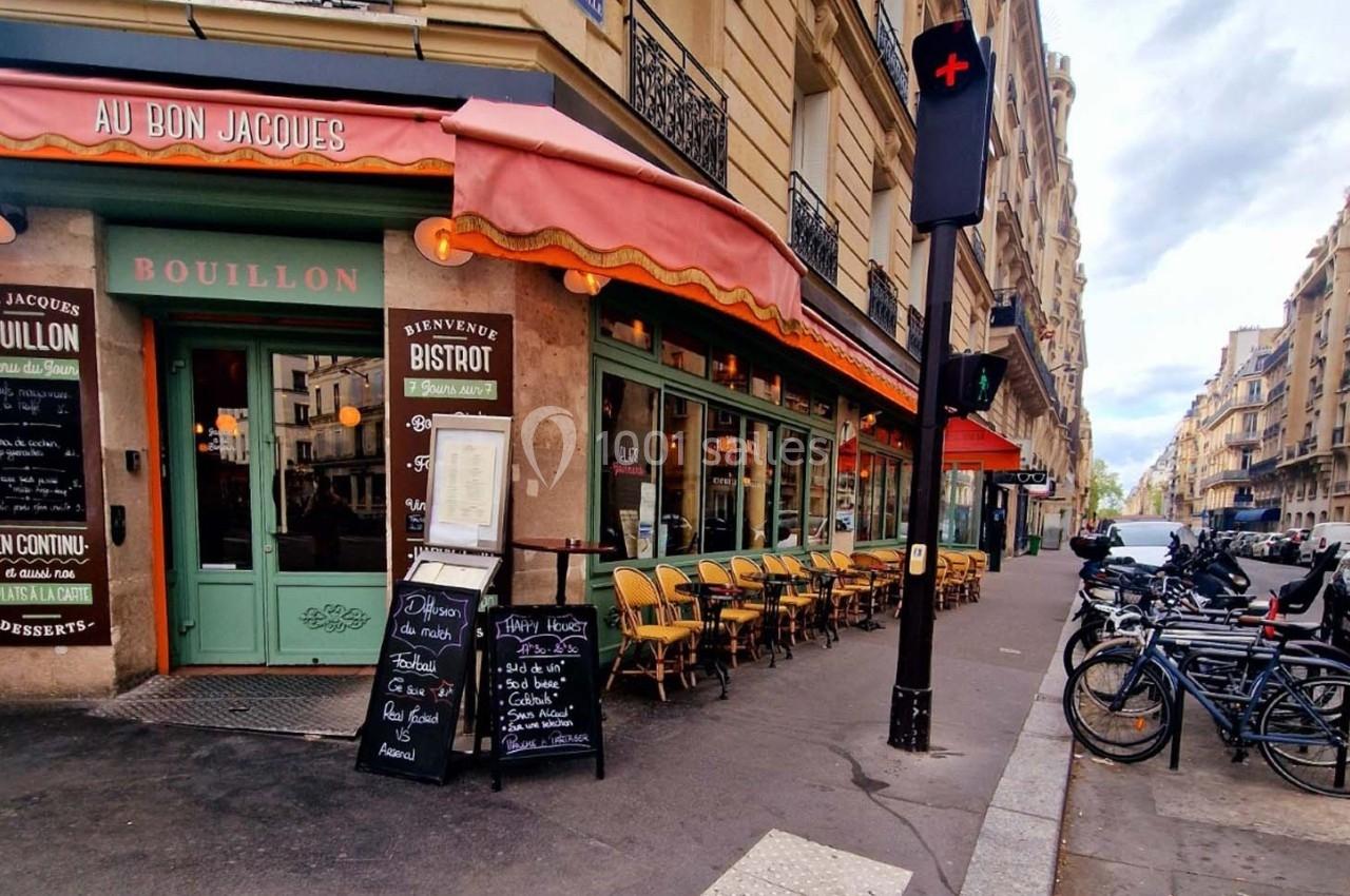 Façade d'un bistrot parisien avec terrasse, chaises alignées, menu affiché et vélos stationnés à proximité.