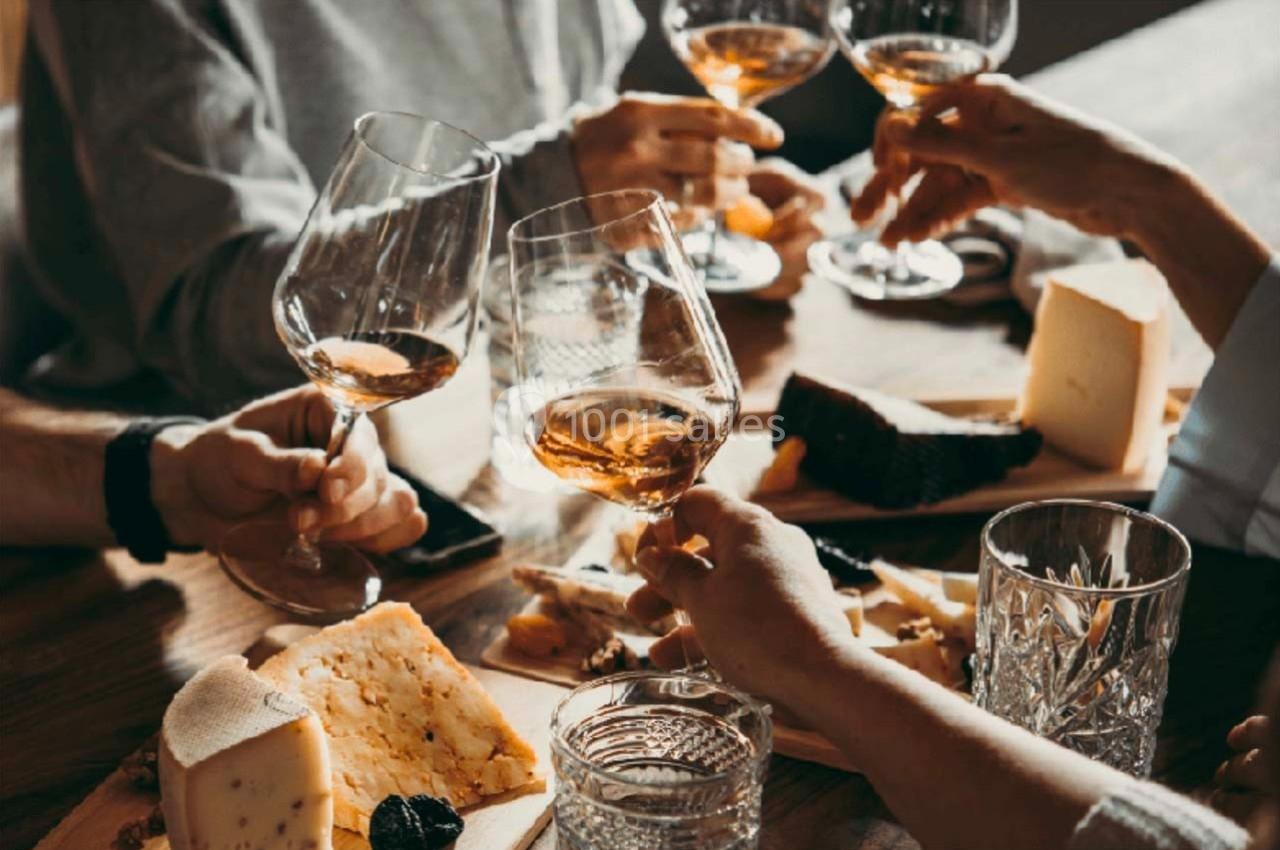 Personnes trinquant avec des verres de vin autour d'une table garnie de fromages et de charcuteries.