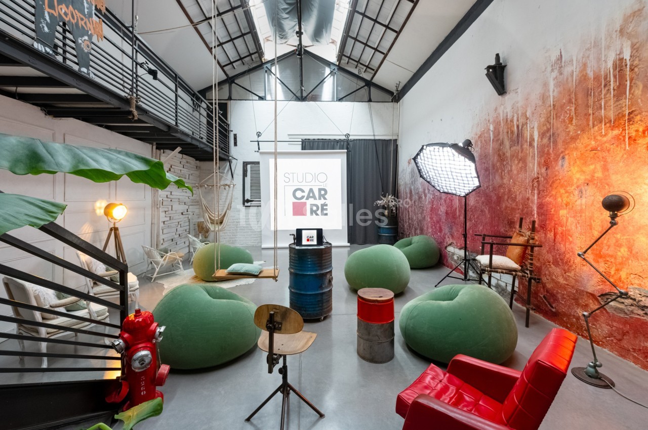 Salle aménagée avec des fauteuils, un écran de projection, des éclairages et une décoration industrielle colorée.