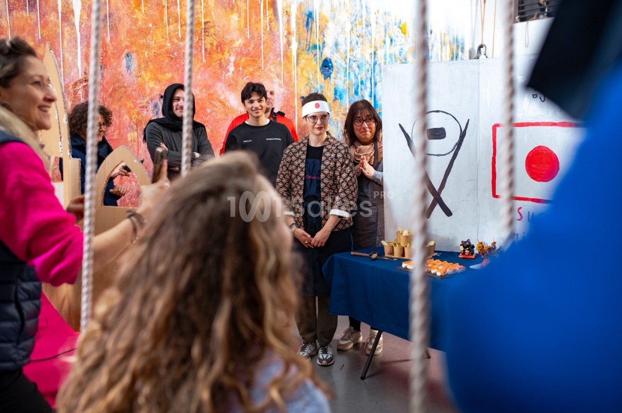 Un groupe de personnes participe à une activité artistique dans un atelier coloré avec des décorations murales.