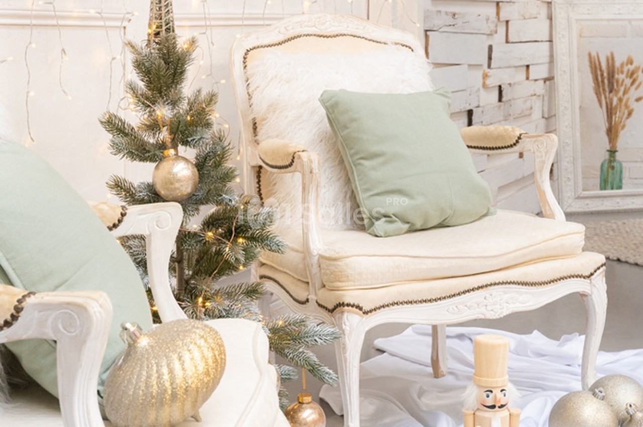 Fauteuils anciens avec coussins verts, sapin décoré de boules dorées et casse-noisette dans un décor lumineux et festif.