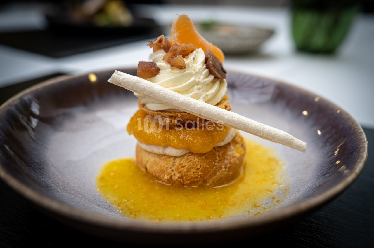 Pâtisserie garnie de crème, segments de mandarine, éclats de noix et sauce orange, décorée d'une meringue.