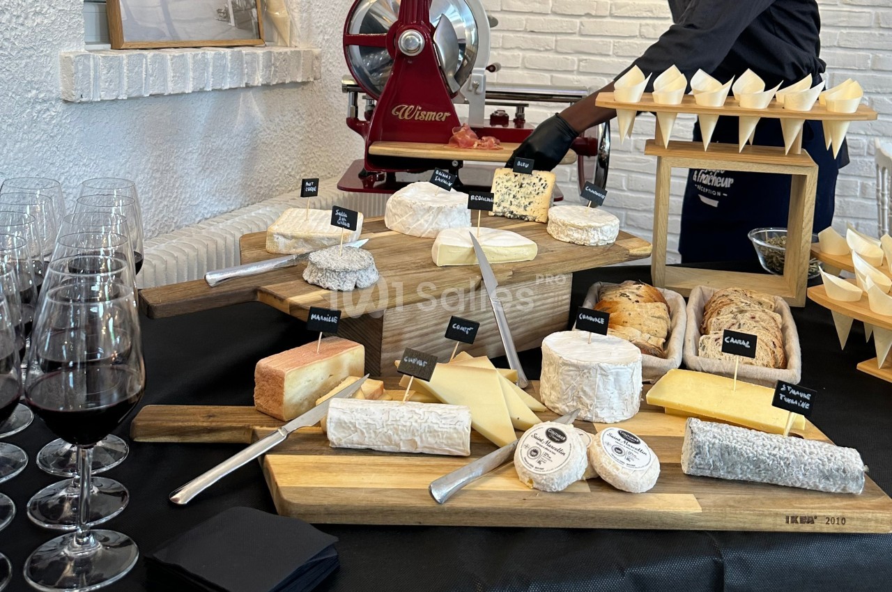 Plateau de fromages variés disposés sur des planches en bois, accompagné de couteaux et de verres de vin rouge.