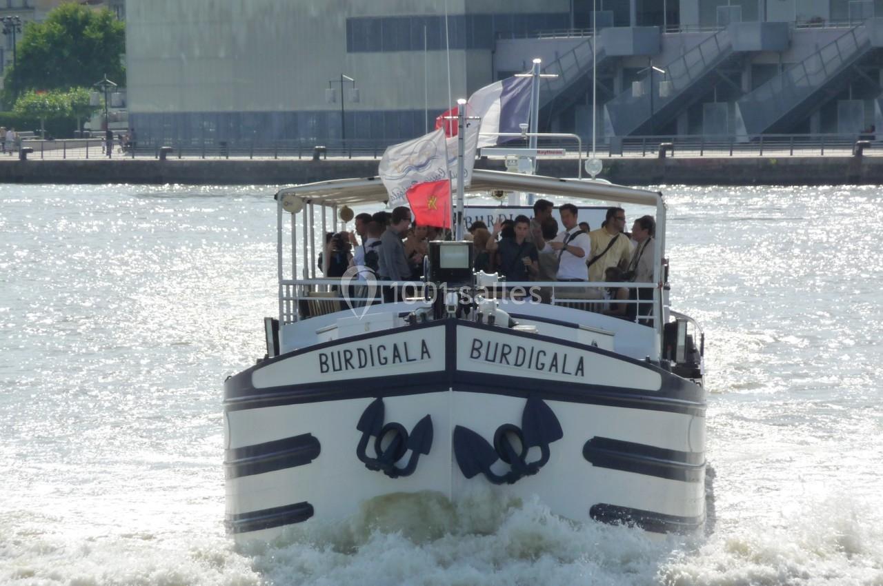 Bateau de croisière fluvial ’Burdigala’ naviguant sur une rivière avec des passagers à bord.