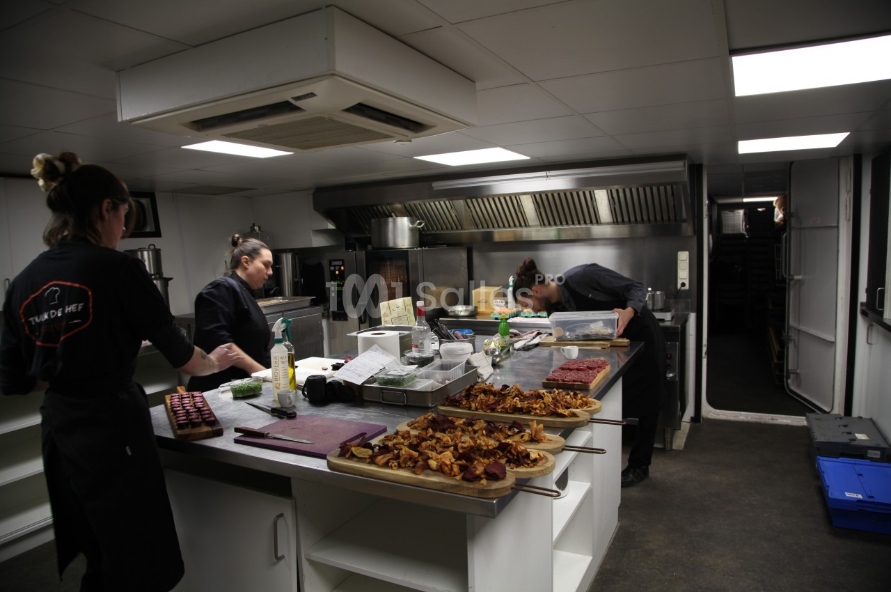 Trois cuisiniers préparent des plats dans une cuisine professionnelle équipée, avec des assiettes déjà dressées au premier…