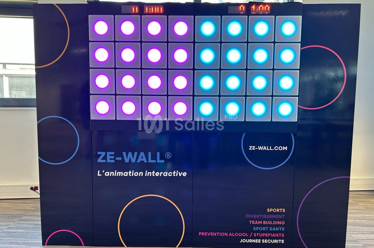 Mur interactif lumineux avec des cases colorées éclairées, utilisé pour des activités sportives et ludiques en intérieur.