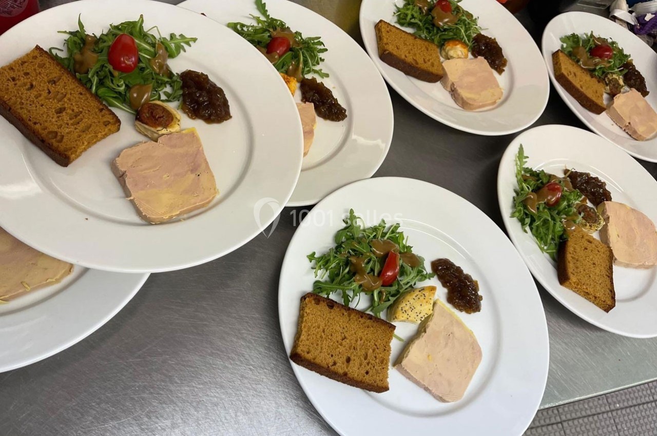 Assiettes dressées avec du foie gras, pain d'épices, chutney et salade verte garnie de tomates cerises.
