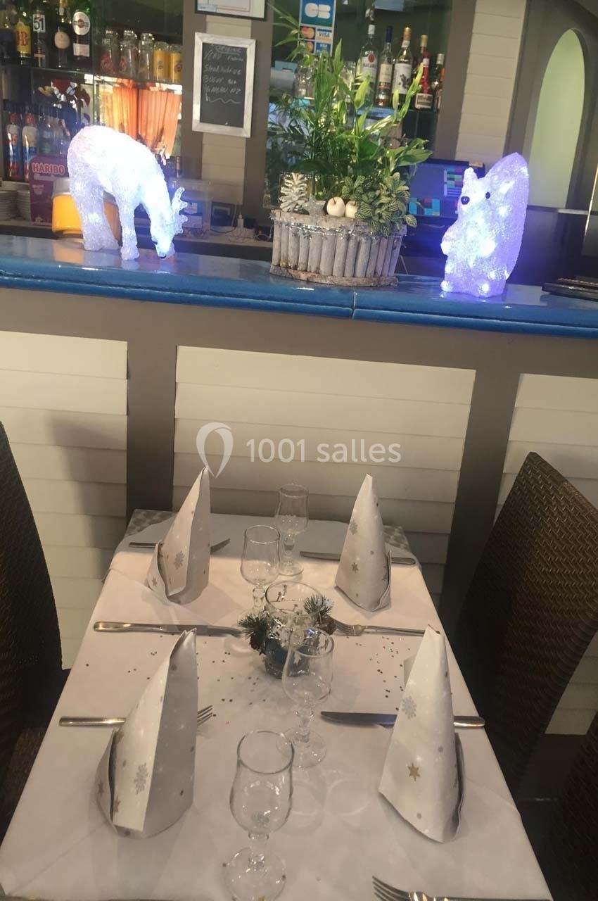 Table dressée pour un repas festif avec décorations lumineuses en forme d'ours et de renne sur un comptoir en arrière-plan.