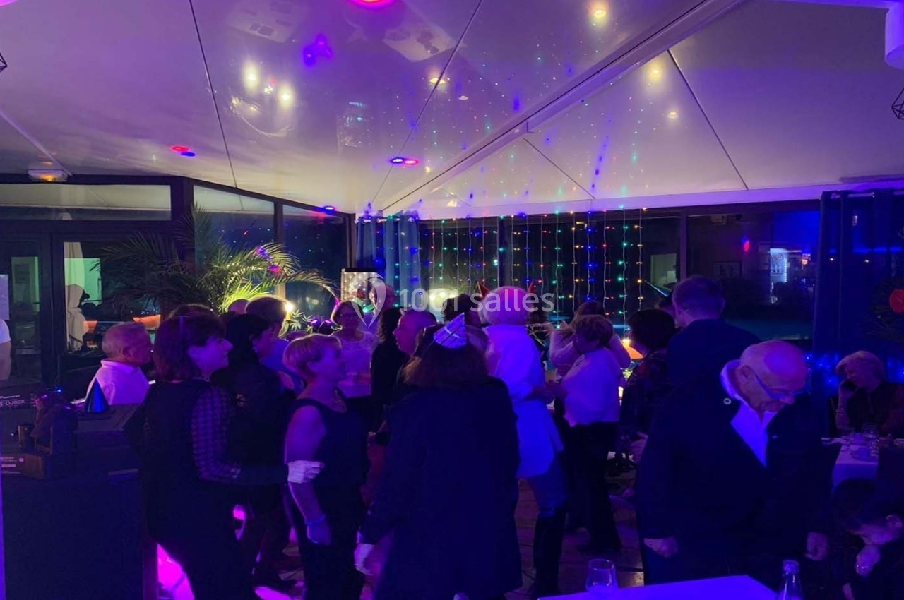 Groupe de personnes dans une salle éclairée par des lumières colorées, semblant participer à une fête ou un événement.