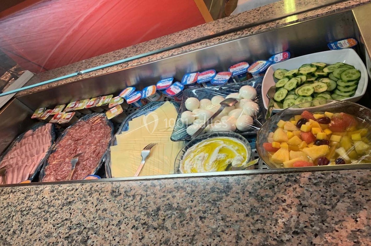 Buffet froid avec charcuterie, fromage, œufs durs, tranches de concombre, salade de fruits et portions de beurre.
