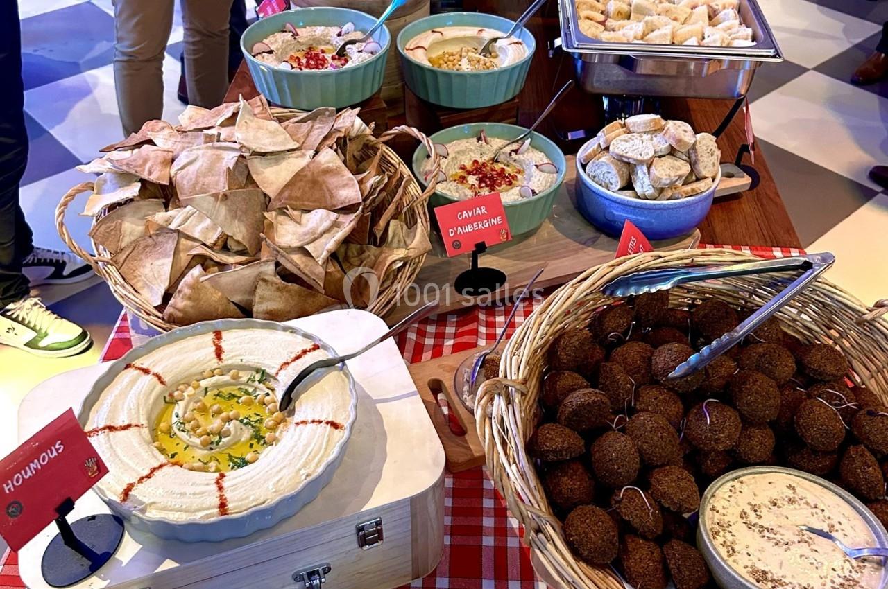 Buffet avec houmous, falafels, pain pita, caviar d’aubergine et autres plats méditerranéens disposés sur une table.