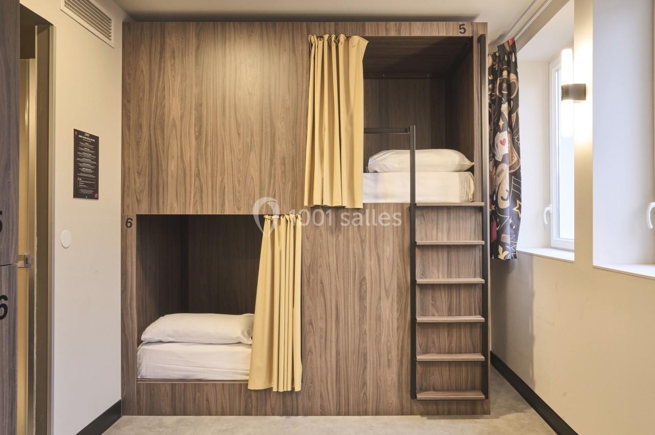 Lits superposés en bois avec rideaux jaunes dans une chambre lumineuse, échelle et fenêtres sur le côté.