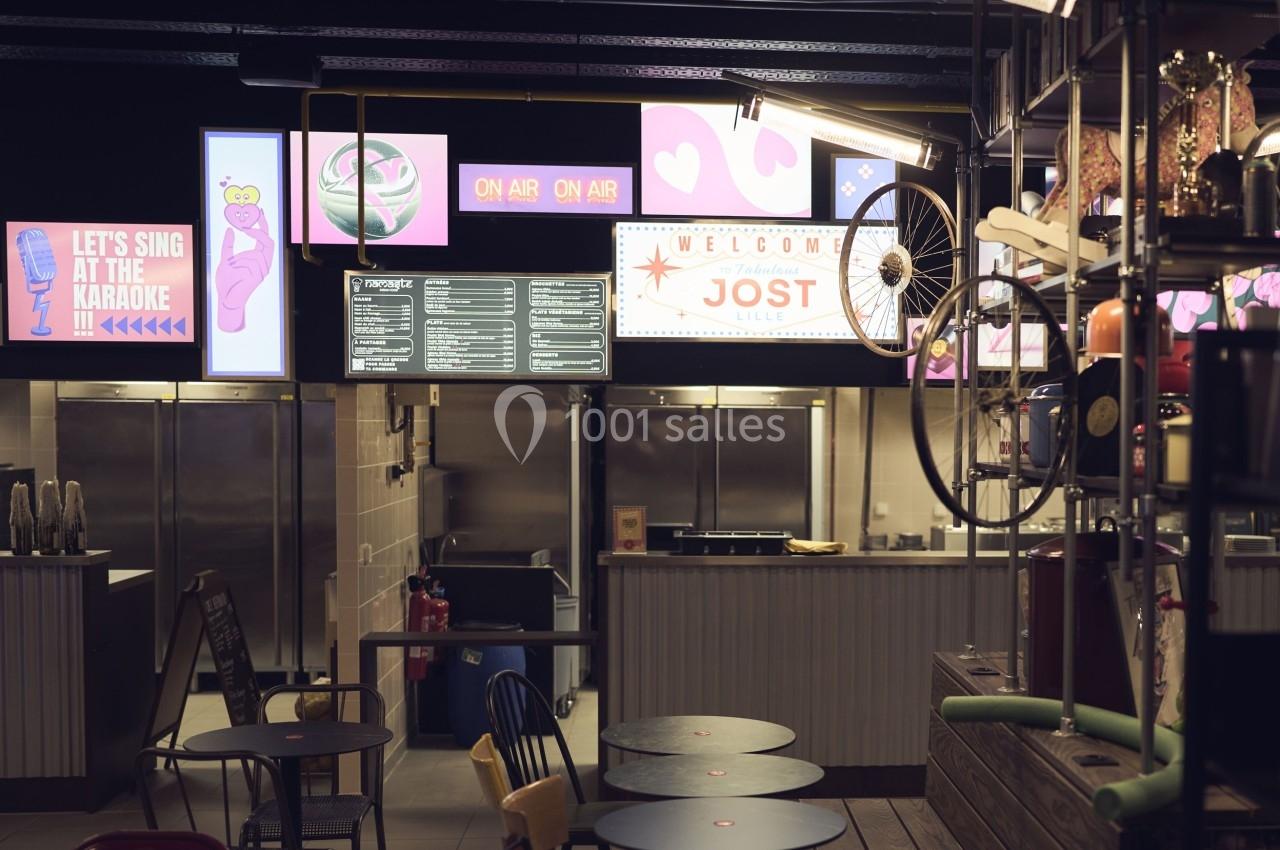 Intérieur d'un espace de restauration avec comptoirs, menus affichés et décorations lumineuses colorées.