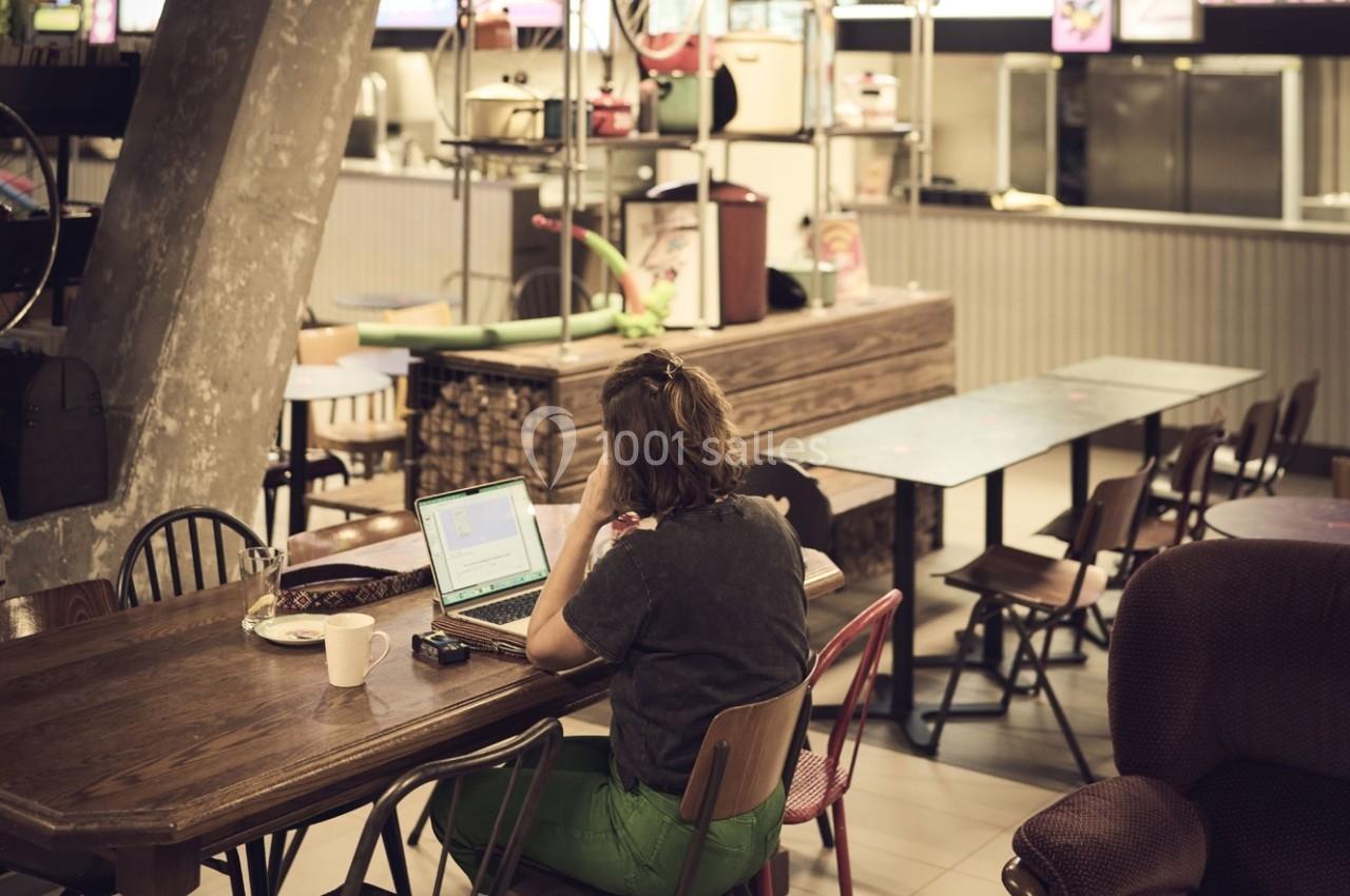 Une personne travaille sur un ordinateur portable dans un espace de restauration partiellement vide.