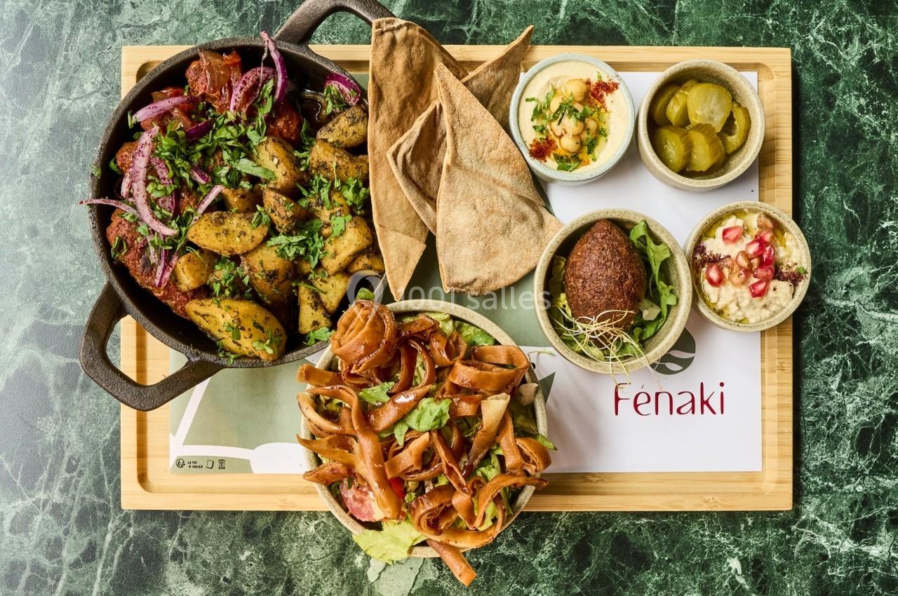 Plateau de mezzés variés avec légumes rôtis, falafel, houmous, pain pita et accompagnements sur une table en marbre.