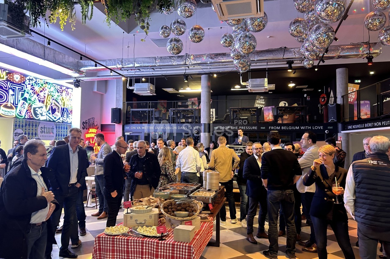 Groupe de personnes échangeant dans un espace intérieur décoré avec des guirlandes lumineuses et des tables de buffet.
