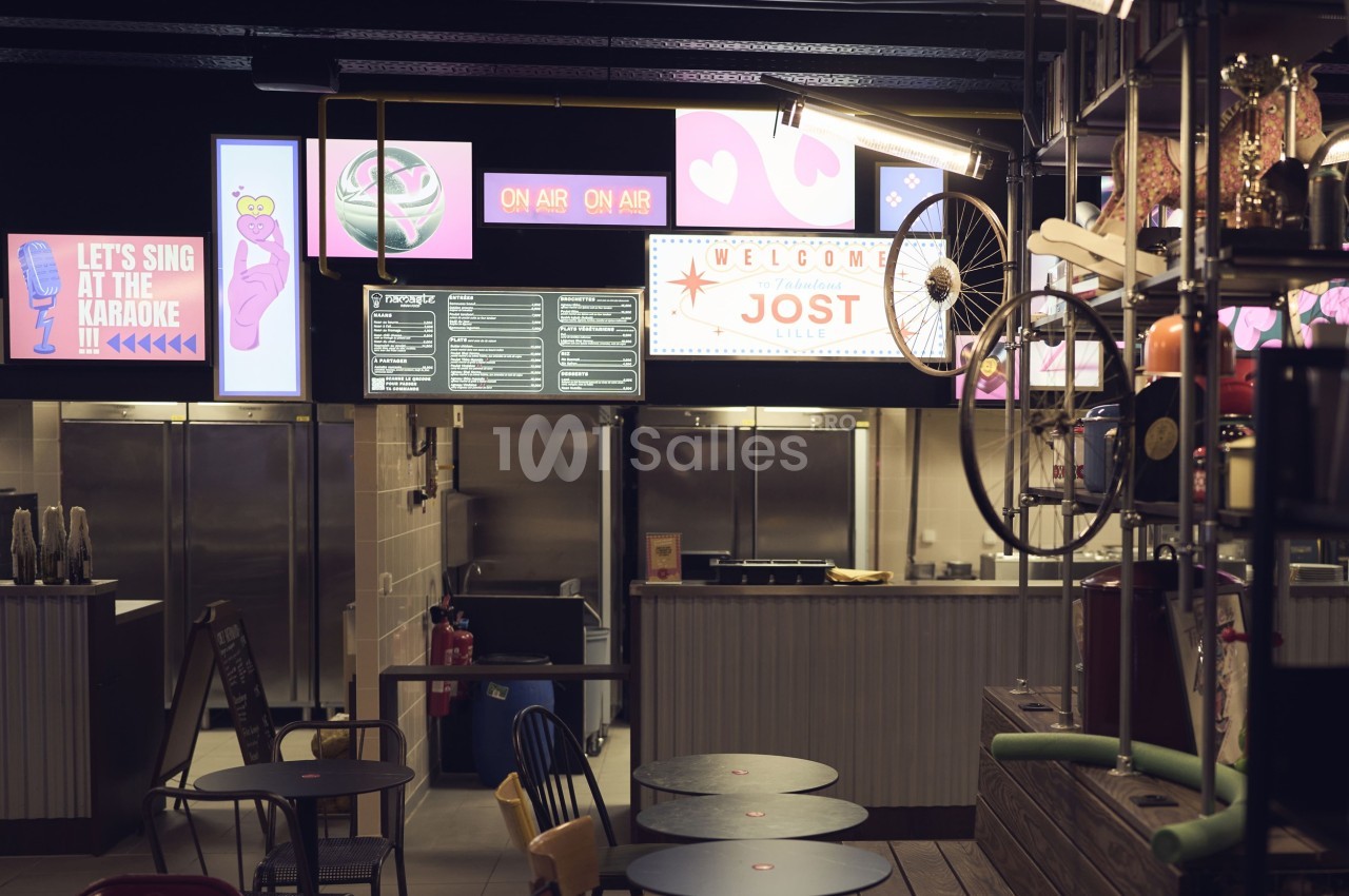 Intérieur d'un espace de restauration avec comptoirs, menus affichés et décorations lumineuses colorées.