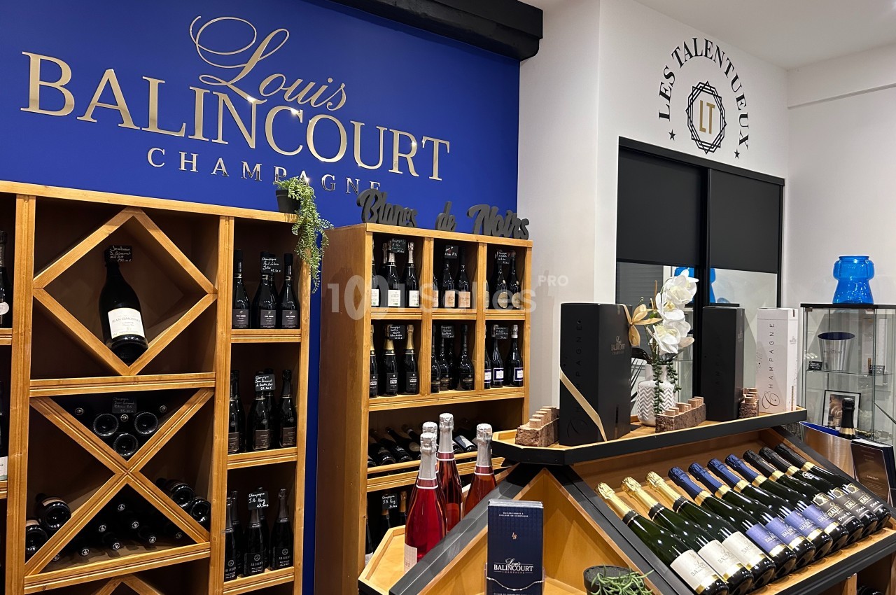 Rayonnages de bouteilles de champagne et de vin exposés dans une boutique avec une enseigne ’Louis Balincourt’.