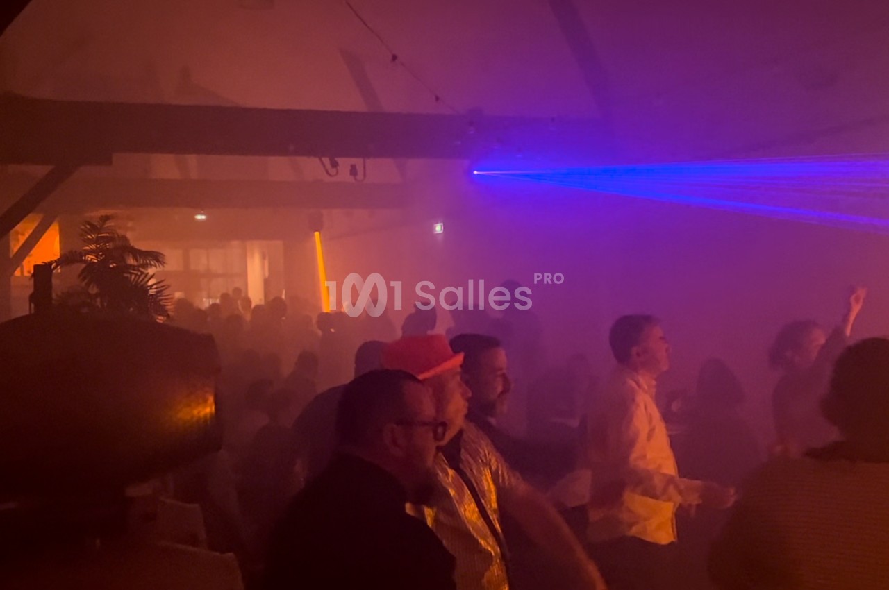 Groupe de personnes dans une salle sombre avec des lumières colorées et un faisceau laser bleu.