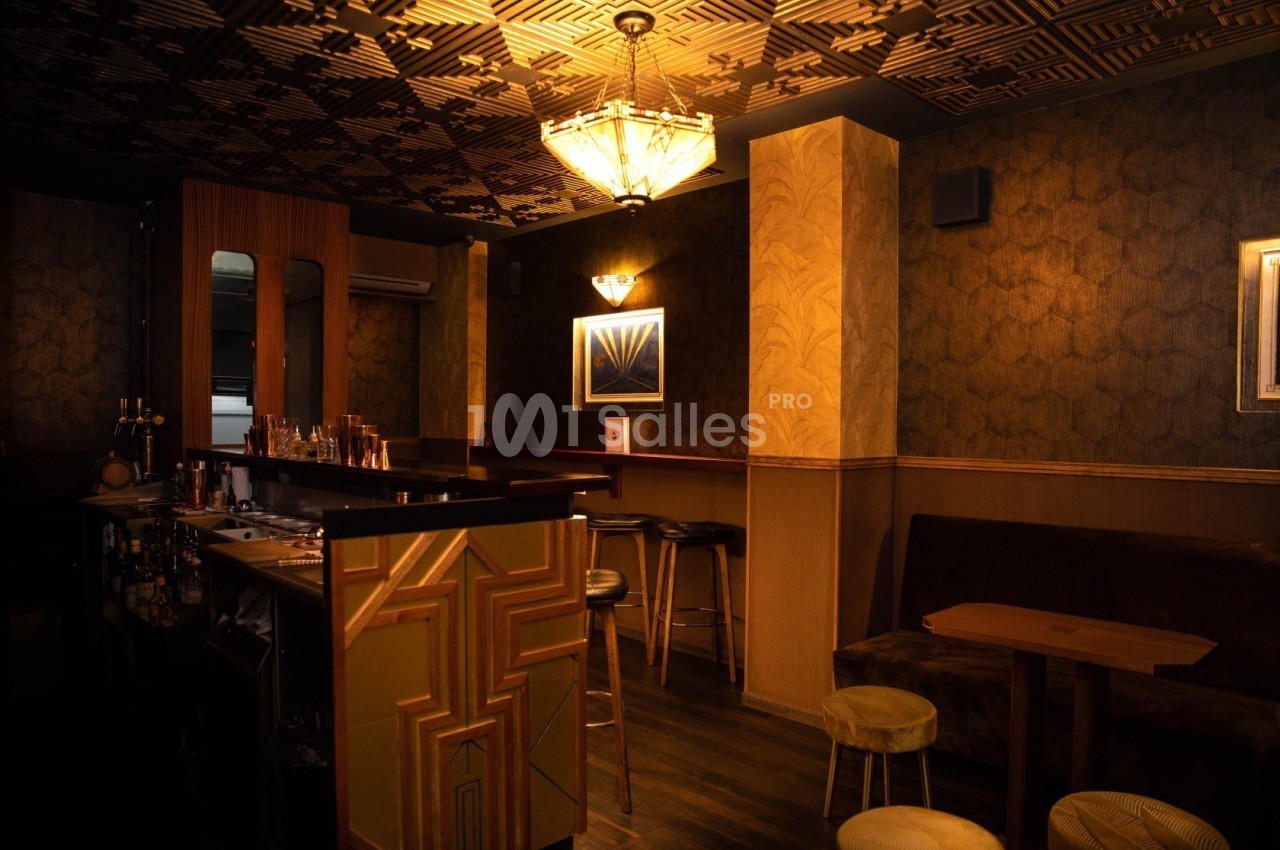Intérieur d'un bar à l'ambiance feutrée avec éclairage tamisé, mobilier en bois et décorations art déco.