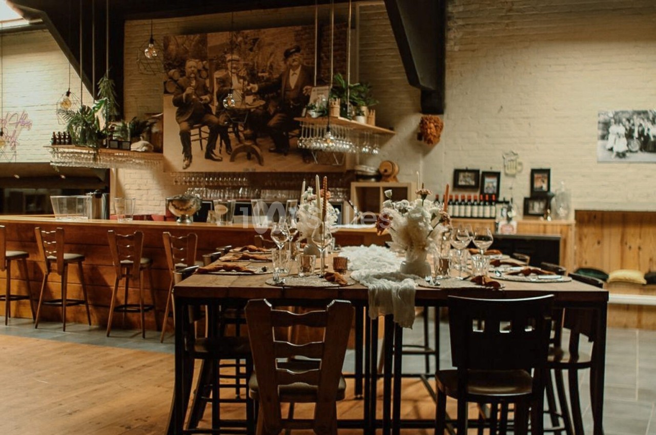 Table dressée avec des chandeliers et des fleurs dans un intérieur chaleureux avec un bar en bois en arrière-plan.