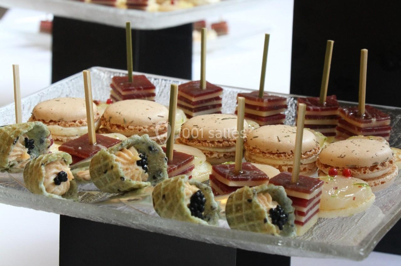 Plateau de bouchées apéritives variées comprenant macarons salés, gelées en couches et cônes garnis de crème et caviar.