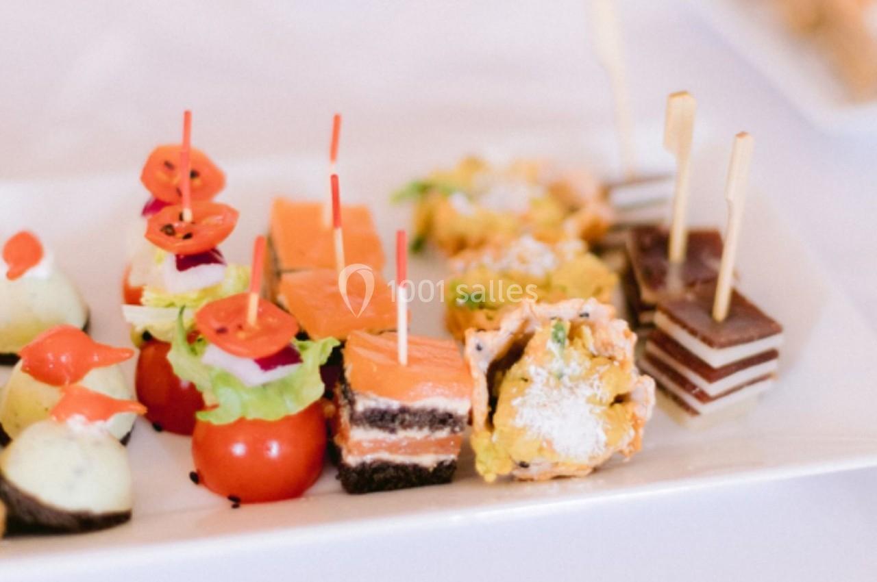 Assortiment de bouchées apéritives variées, incluant légumes, saumon, gâteaux salés et sucrés sur un plateau blanc.