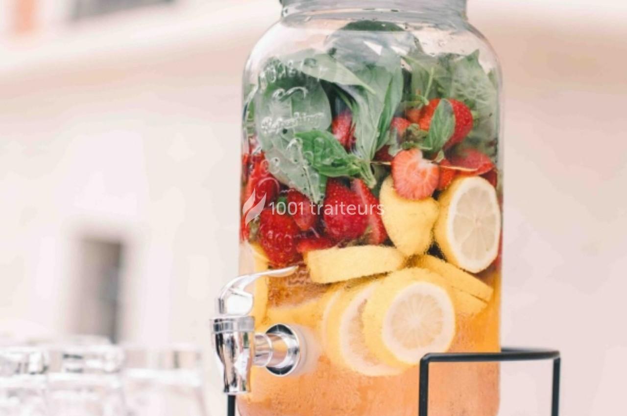 Distributeur de boisson contenant de l'eau infusée avec des fraises, des citrons et des feuilles de menthe.
