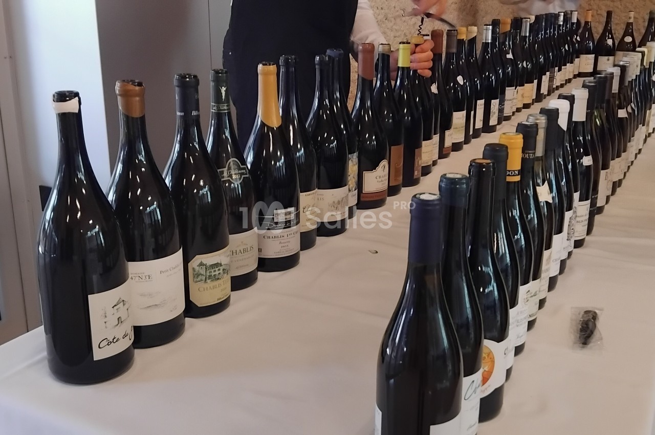 Bouteilles de vin alignées sur une table blanche lors d'une dégustation ou d'un événement œnologique.