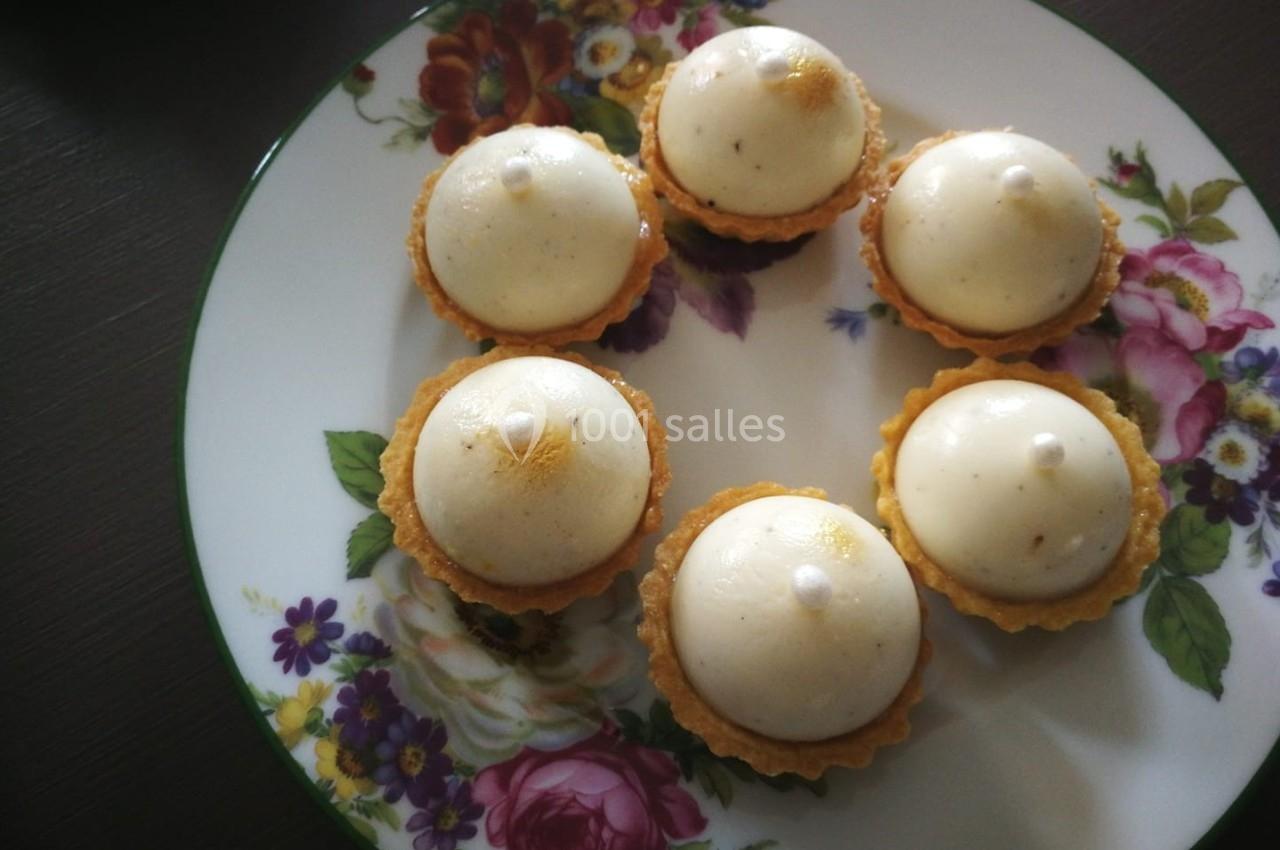 Assiette décorée contenant six tartelettes garnies de mousse blanche, disposées en cercle.