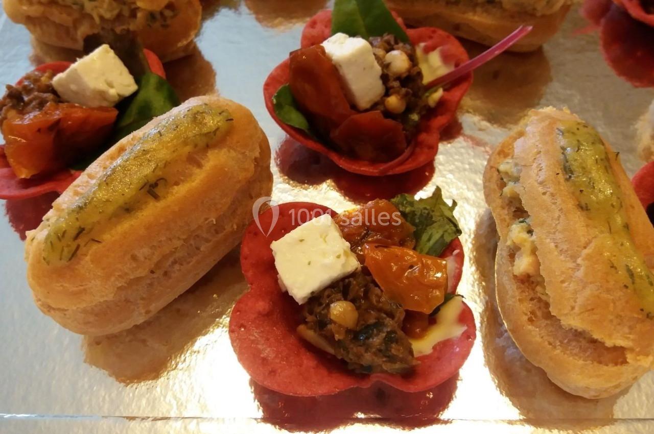Assortiment de bouchées salées comprenant éclairs garnis et fleurs comestibles avec légumes et fromage.