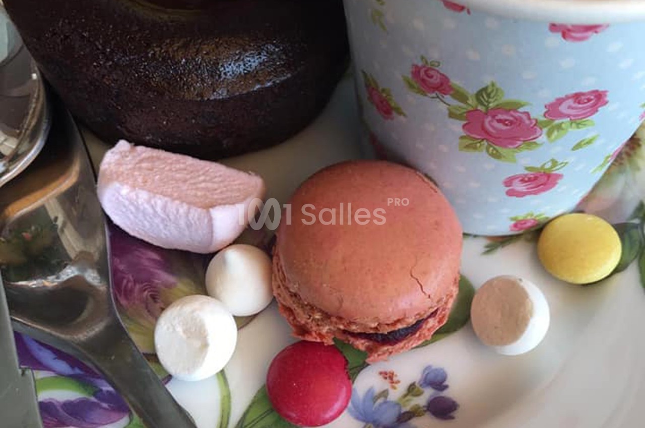 Assiette avec un macaron rose, des bonbons colorés, une guimauve, un gâteau au chocolat et une tasse fleurie.