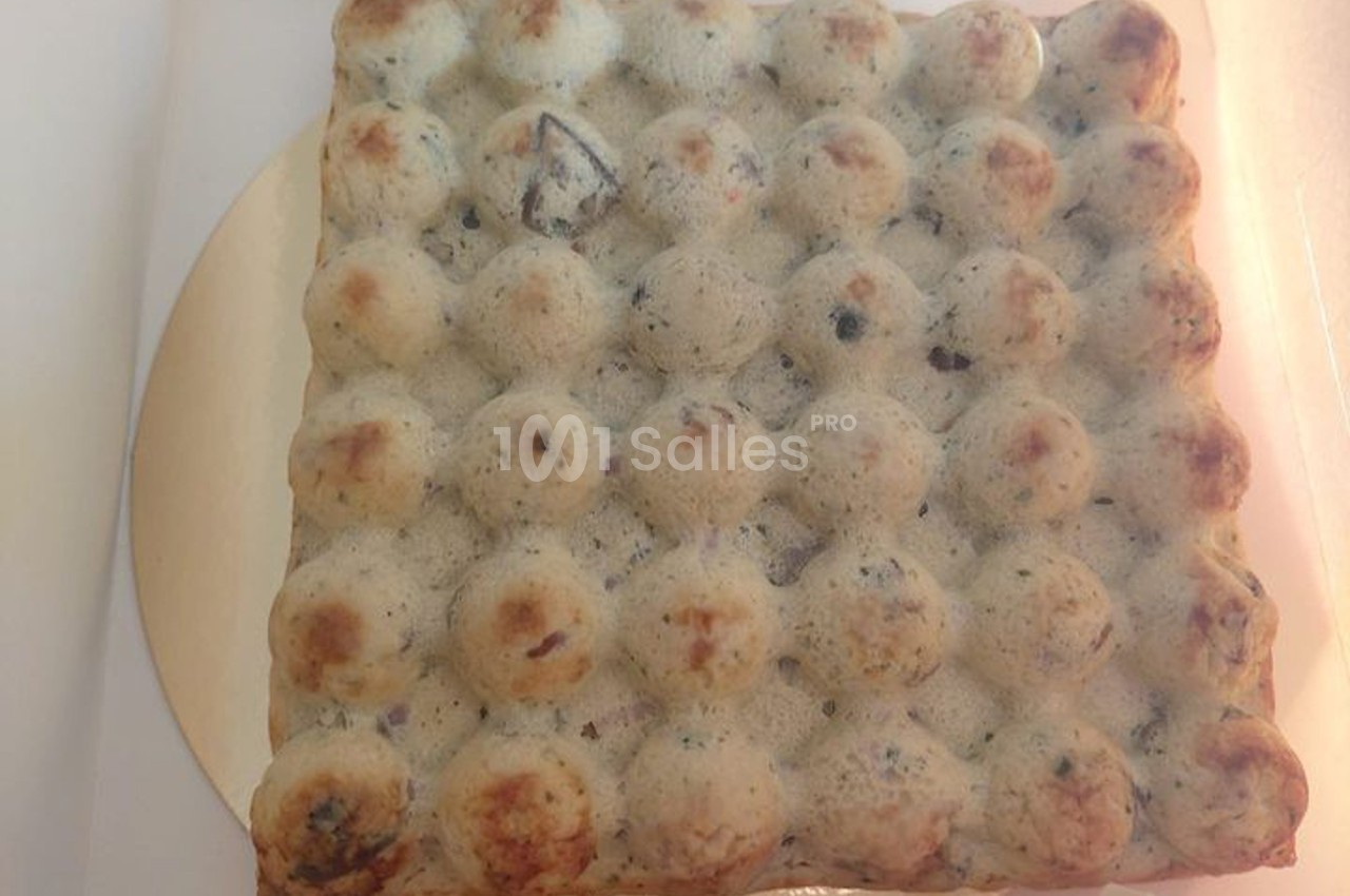 Gaufre carrée à bulles, légèrement dorée, avec des inclusions sombres visibles dans la pâte.