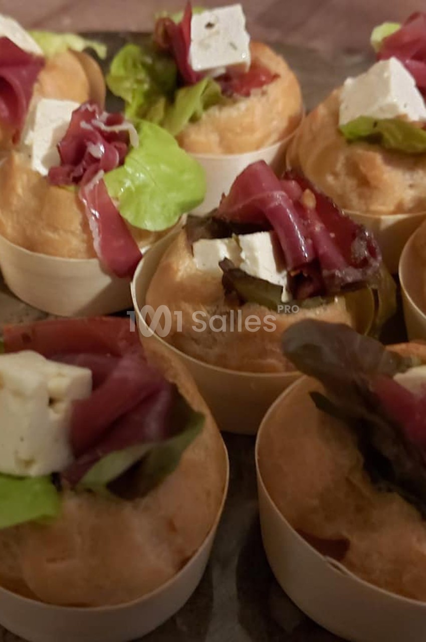 Petits choux garnis de salade, fromage frais et lamelles de viande séchée, présentés sur un plateau.